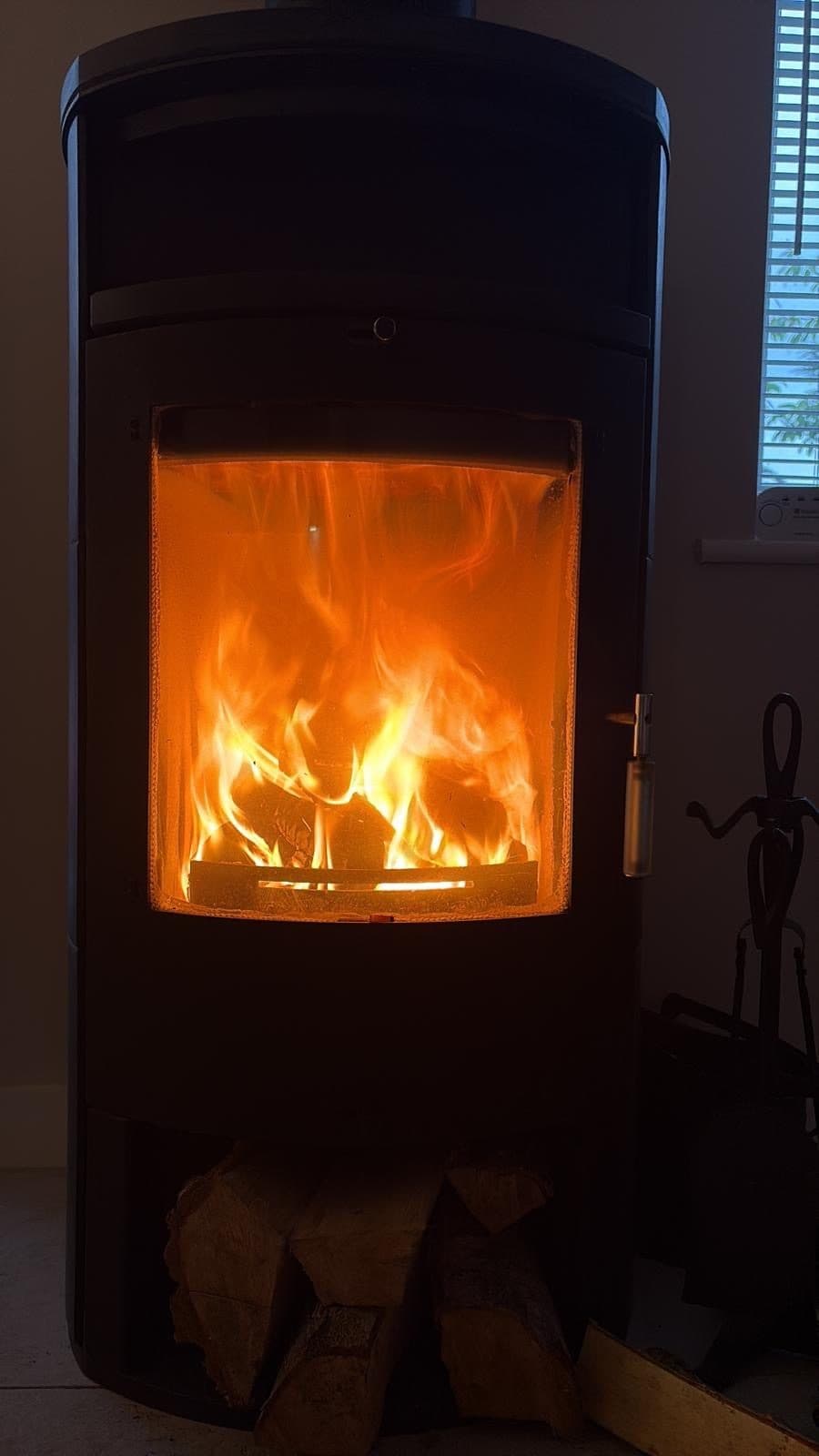 Curved-glass black stove with a full fire burning behind the door